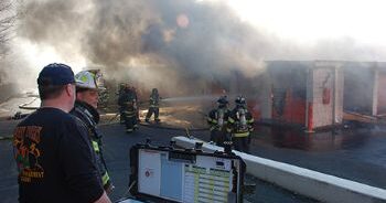 A firefighter commanding teams at a fire with a mobile command board.